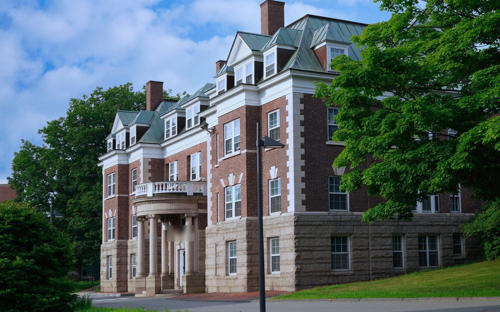 Brick university residence hall with a columned entrance among trees